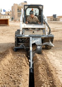 US Navy 070515-N-3560G-005 Equipment Operator 3rd Class Stephen Dixson of Naval Mobile Construction Battalion (NMCB) 4 digs a telephone line trench using a Bobcat trencher
