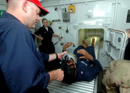 US Navy 070517-N-1226D-046 Damage Controlman 1st Class Myles Fry, from San Bernardino, Calif., removes a MCU2-P gas mask from Damage Controlman 3rd Class Ricardo Delacruz, from Ft. Myers, Fla., prior to performing decontaminati