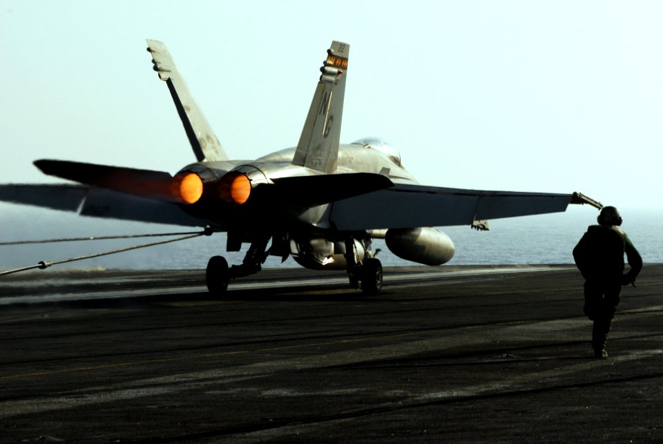 US Navy 070518-N-2659P-249 Airman Apprentice Zach Bray from air department's launch and recovery division hurries to ensure the tailhook releases the arresting gear wire after the recovery of an F-A-18C Hornet