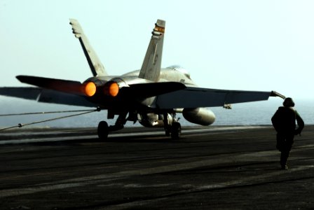US Navy 070518-N-2659P-249 Airman Apprentice Zach Bray from air department's launch and recovery division hurries to ensure the tailhook releases the arresting gear wire after the recovery of an F-A-18C Hornet