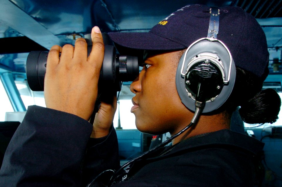 US Navy 070518-N-4420S-115 Operations Specialist Seaman Caitlyn Hagedorn looks through a pair of binoculars while standing lookout watch aboard nuclear-powered aircraft carrier USS Nimitz (CVN 68)