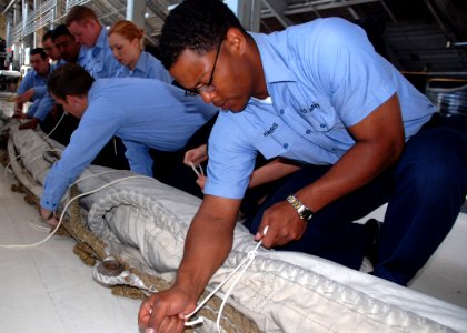 US Navy 070524-N-2893B-001 In the Navy Yard's USS Constitution Repair Facility, Seaman Brian Harris ties up a 500-lb., 158-sq. ft. mizzen sail in preparation for transporting it to the wood-hulled, three-masted frigate