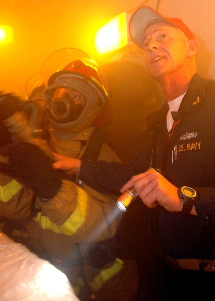 US Navy 070523-N-5928K-008 Ship's Fire Marshall, Chief Warrant Officer Jeff Lomax, instructs a nozzle man on proper fire fighting techniques during a simulated fire in the jet shop during a general quarters