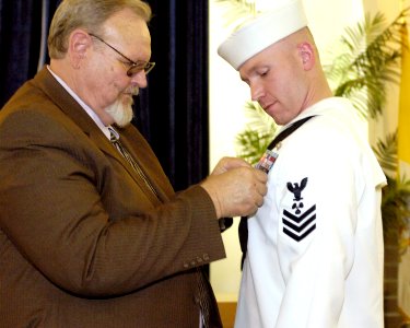US Navy 070530-N-8467N-003 Dr. William C. Duke pins the Bronze Star on his son Machinist's Mate 1st Class Caleb S. Duke