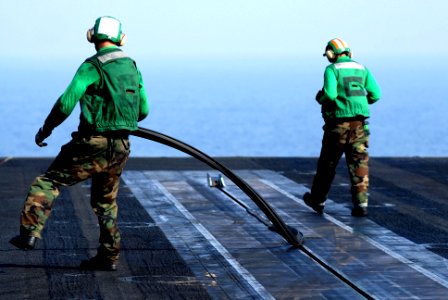 US Navy 070525-N-5484G-004 Aviation Boatswain's Mate (Equipment) Airman Ryan Martin removes a protective cover that prevents foreign object debris from falling into the catapult while preparing for flight operations aboard nucl