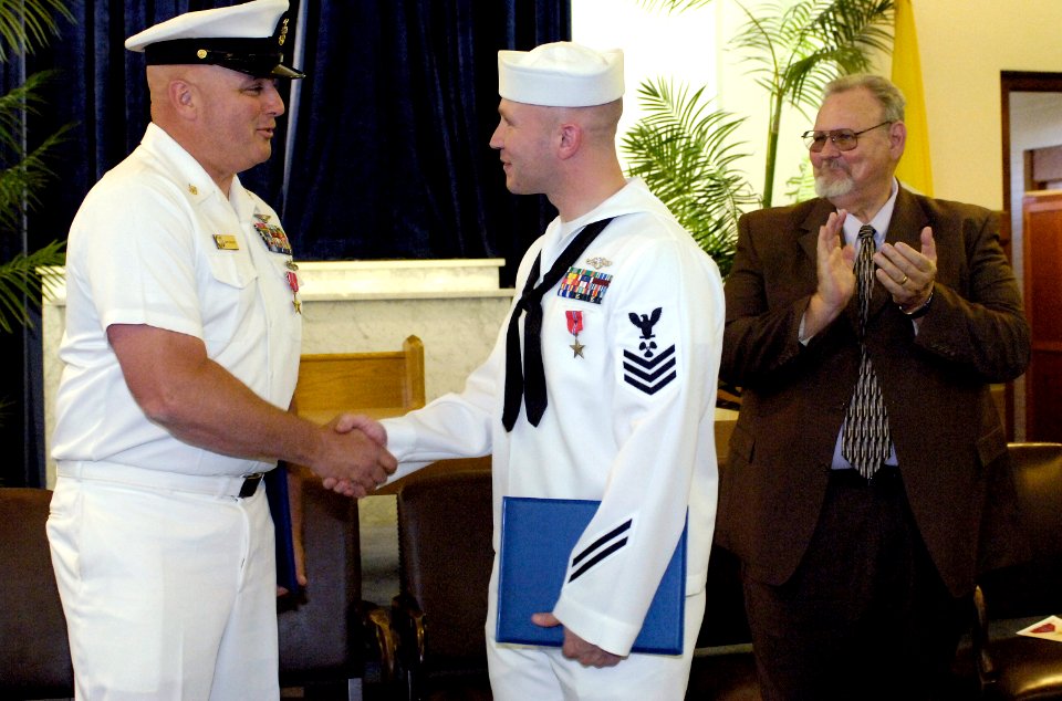 US Navy 070530-N-8467N-004 Master Chief Aviation Ordnanceman Gary Mason shakes the hand of Machinist's Mate 1st Class Caleb S. Duke as his father Dr. William C. Duke, who earned a Bronze Star for his service in Vietnam, l