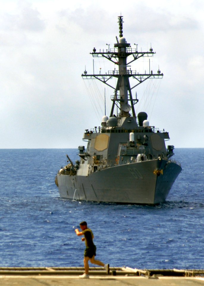US Navy 070529-N-5067K-028 A Marine runs the flight deck of amphibious transport dock USS Juneau as Arleigh Burke-class destroyer USS Paul Hamilton (DDG 60) steams alongside