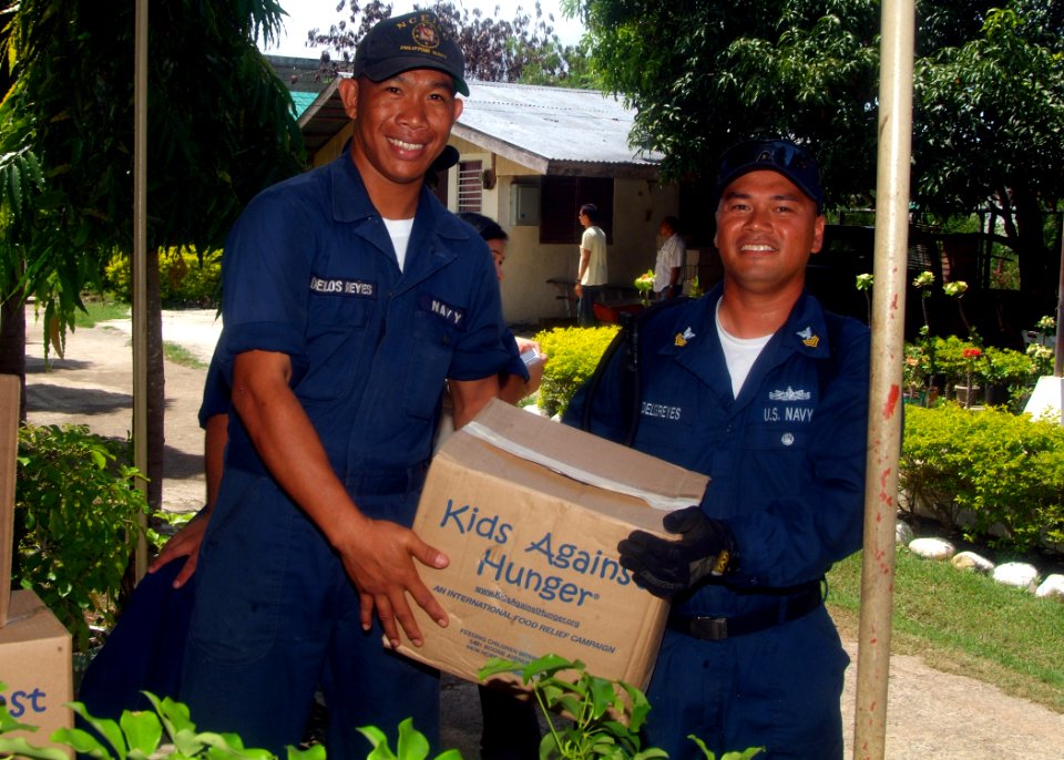 US Navy 070531-N-0120A-056 Boatswain Mate 1st Class Roy Delosreyes, a USS Harpers Ferry (LSD 49) Sailor, stops unloading supplies to pose for a picture