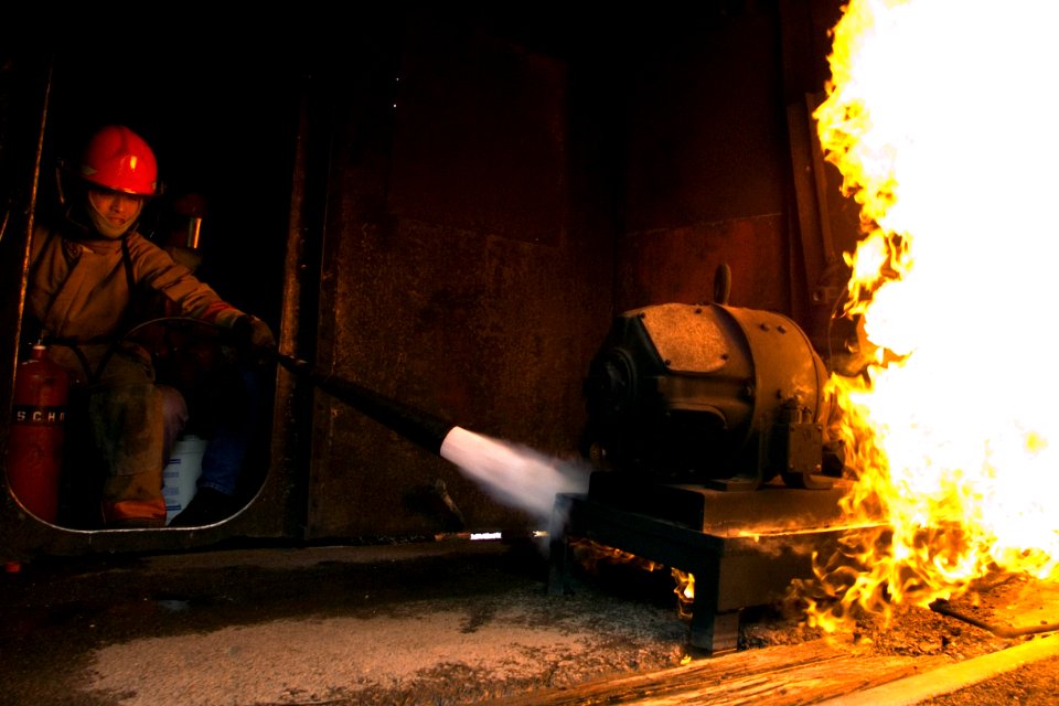 US Navy 070606-N-3390M-002 Ensign Binh Nguye assigned to Arleigh Burke class guided missile destroyer USS Shoup (DDG 86) extinguishes a simulated class C fire during firefighting training at Fremont Maritime Services