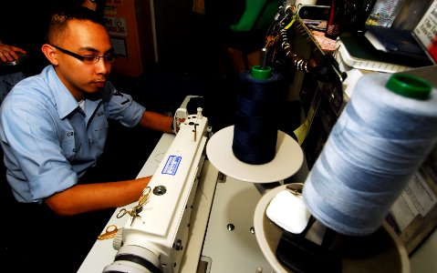 US Navy 070601-N-9928E-031 Ship's Serviceman 3rd Class Jonathan Cruz sews a 3rd class rating badge onto a set of coveralls in the tailor shop aboard the Nimitz-class aircraft carrier USS John C. Stennis (CVN 74)