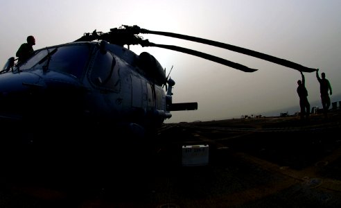 US Navy 070603-N-0684R-008 Flight deck personnel work together to spread the blades of an SH-60B Seahawk attached to the Wolfpack of Helicopter Anti-Submarine Light Squadron (HSL) 45 on the flight deck of the guided-missile USS