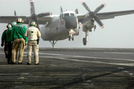 US Navy 070603-N-0890S-032 Sailors standby as an C-2 Greyhound assigned to the Providers of Carrier Logistics Support Squadron (VRC) 30 lands on the flight deck of the nuclear-powered aircraft carrier USS Nimitz (CVN 68)