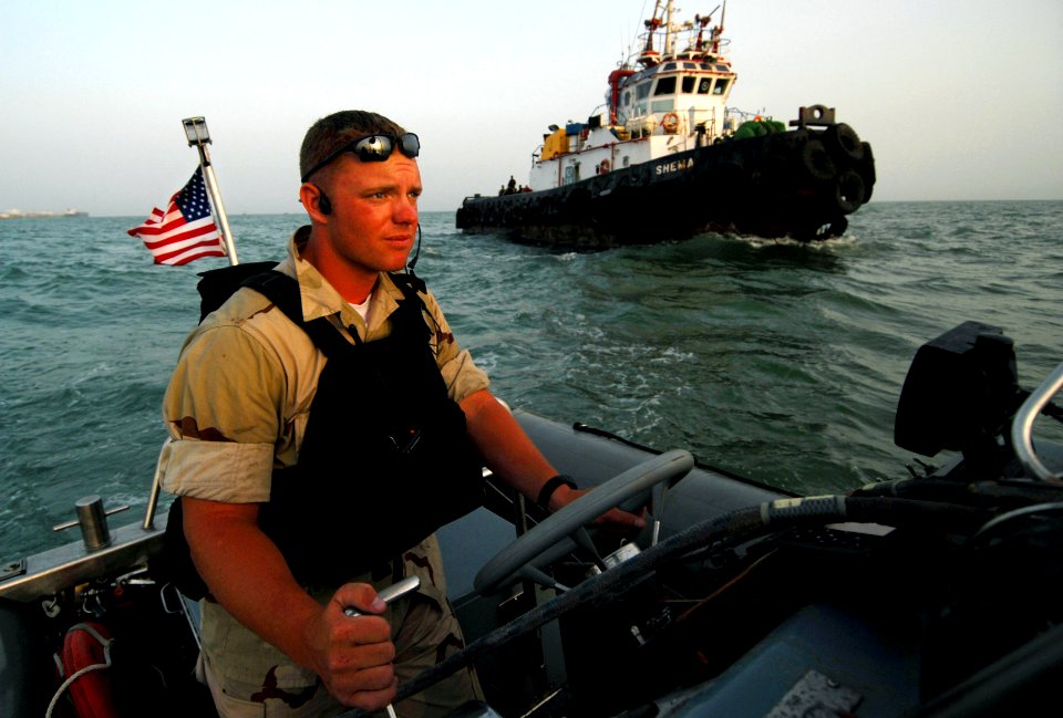 US Navy 070604-N-0684R-131 Seaman Kevin Bruton, from the visit, board, search and seizure (VBSS) team assigned to guided-missile destroyer USS Preble (DDG 88), steers a rigid hull inflatable boat around a local tugboat after dr