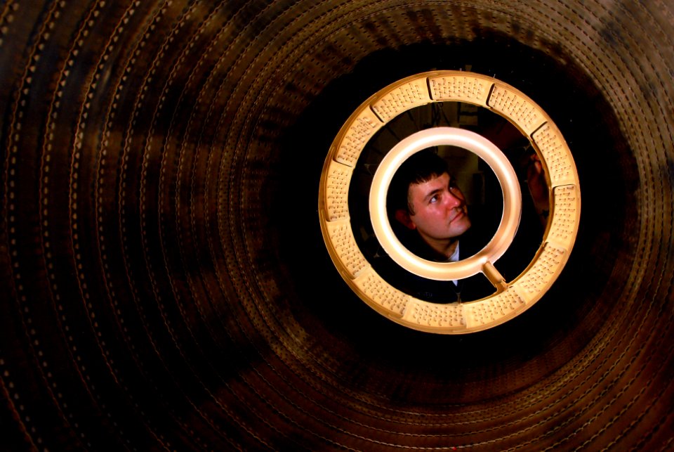 US Navy 070602-N-2659P-106 Aviation Machinist's Mate Airman Shane Cooper inspects the inside of a jet engine after installing fuel sprayers on a jet engine's afterburner system in the jet engine shop aboard the Nimitz-class air