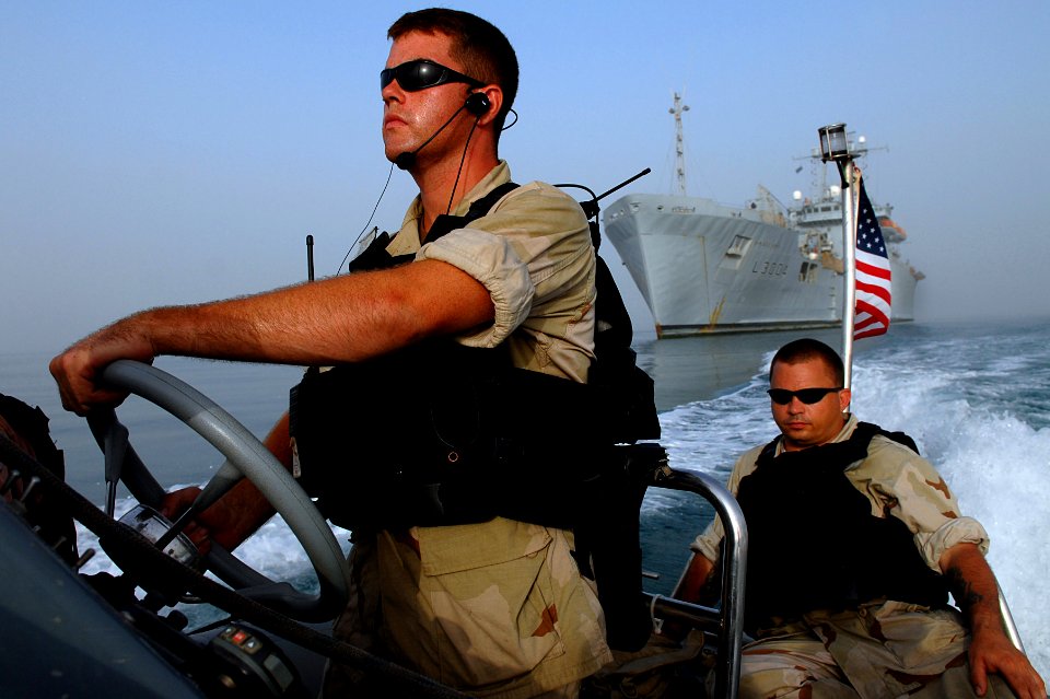 US Navy 070603-N-0684R-289 Engineman 3rd Class Blain Churchill steers a rigid, hull, inflatable boat away from a coalition ship with Engineman 1st Class James Parks