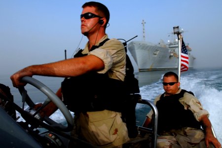 US Navy 070603-N-0684R-289 Engineman 3rd Class Blain Churchill steers a rigid, hull, inflatable boat away from a coalition ship with Engineman 1st Class James Parks