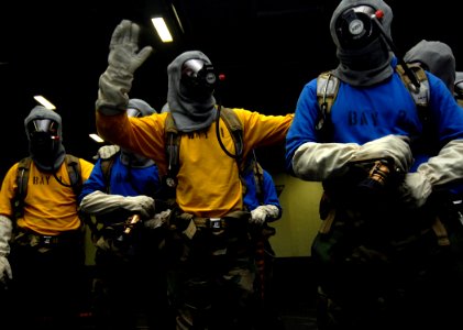 US Navy 070608-N-8923M-005 During a general quarter drill, a Sailor signals to his team leader as a member of the fire team runs low on air while fighting a simulated aircraft fire aboard Nimitz-class aircraft carrier USS Harry