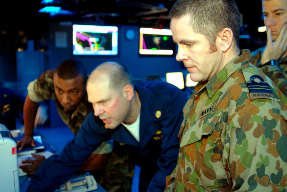 US Navy 070611-N-4124C-029 Royal Australian Navy Lt. Cmdr. Bryan C. Edwards, Australian Fleet Battle Staff liaison officer, looks on as Lt. Cmdr. Gary Larson, of Expeditionary Strike Group 7, pulls up information on a computer