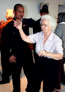 US Navy 070607-N-6710M-034 Hospital Corpsman 2nd Class Rolando Samortin dances with a resident of Wesley Mission's elderly home