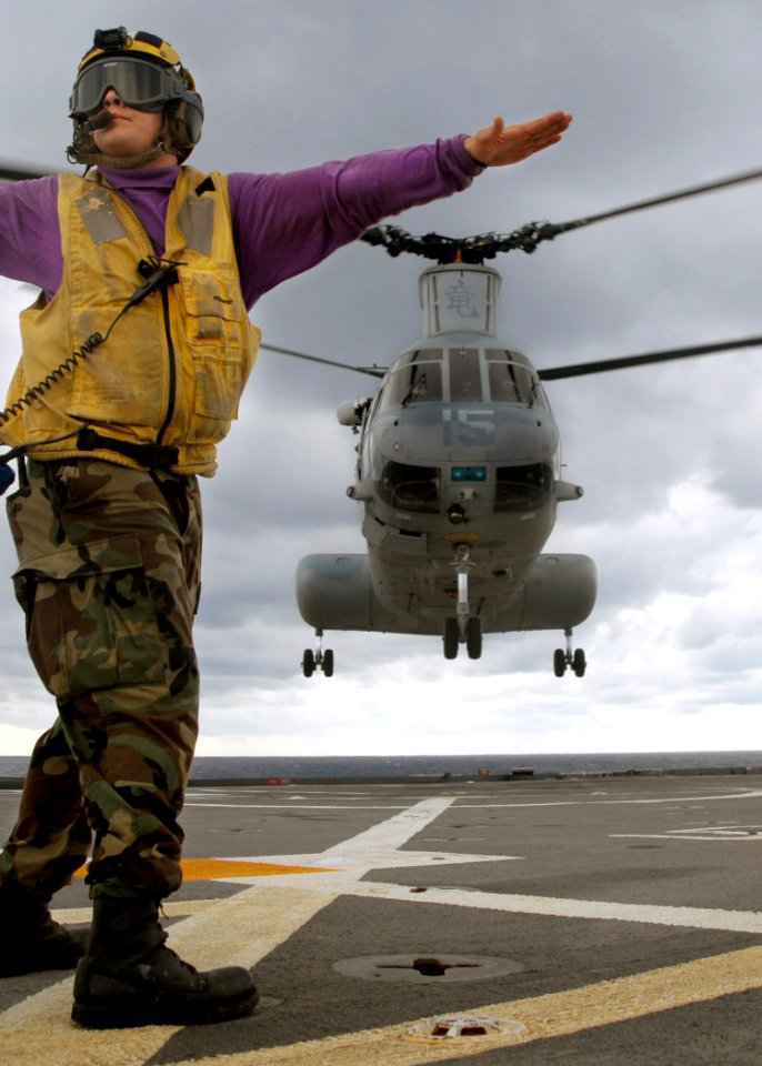 US Navy 070612-N-5067K-062 Aviation Boatswain's Mate Airman Lowel A. Shorey III, a landing signalman enlisted (LSE), signals and checks the horizon for a Marine CH-46 Sea Knight taking-off from amphibious transport dock USS Jun