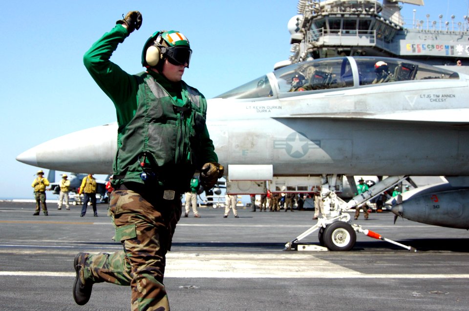 US Navy 070612-N-8119R-056 Aviation Boatswain's Mate Equipment 3rd Class Brent Hoeft runs out of the launch path while signaling that an F-A-18F Super Hornet is attached to the catapult and ready for launch