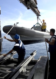 US Navy 070616-N-4954I-014 Boatswain's Mate 3rd Class Tyler Cole holds onto a guide rope in a rigid hull inflatable boat (RHIB) as Sailors help guide the boat into a trailer on board amphibious assault ship USS Peleliu (LHA 5)