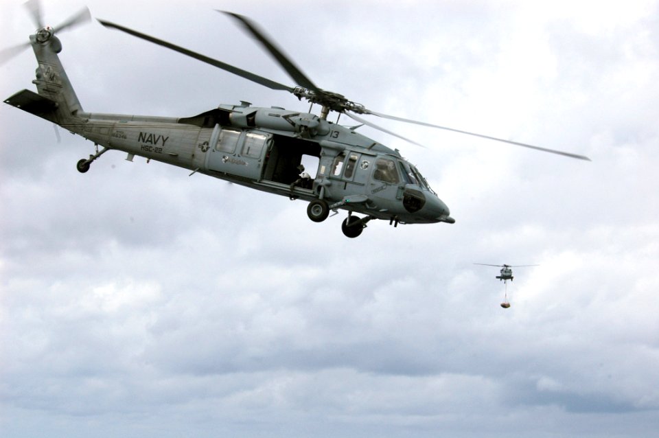 US Navy 070614-N-4014G-096 An MH-60S Seahawk helicopter departs the flight deck of amphibious assault ship USS Kearsarge (LHD 3) after dropping off a pallet of ammunition as a second moves to lower its load