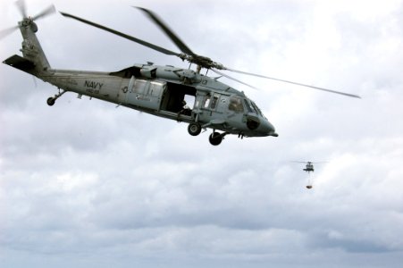US Navy 070614-N-4014G-096 An MH-60S Seahawk helicopter departs the flight deck of amphibious assault ship USS Kearsarge (LHD 3) after dropping off a pallet of ammunition as a second moves to lower its load