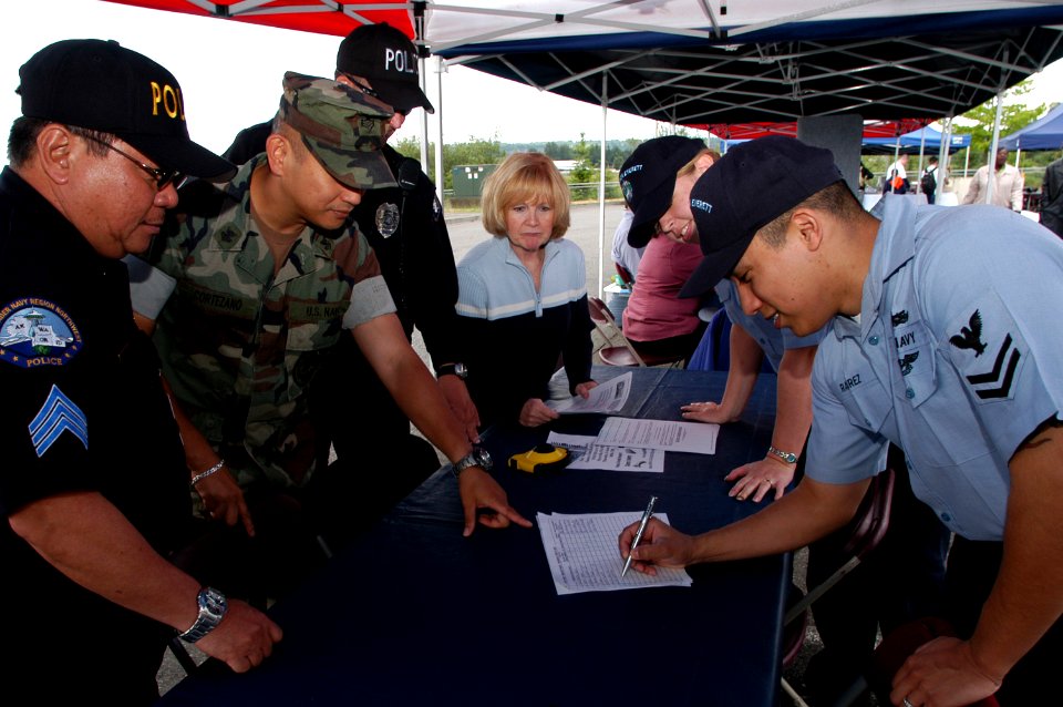 US Navy 070614-N-3390M-001 Religious Program Specialist 2nd Class Delmar Ramirez, right, visits Naval Station Everett's security department recruiting booth at a job fair held at the Smokey Point Naval Support Complex dur