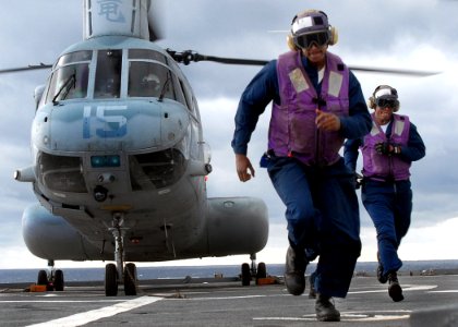 US Navy 070612-N-5067K-113 Aviation Boatswain's Mate (Fuel) Airman Robert D. Cunningham and Aviation Boatswain's Mate (Fuel) Airman Joan R. Abreu hurry as a Marine CH-46 Sea Knight prepares to take off from amphibious transport