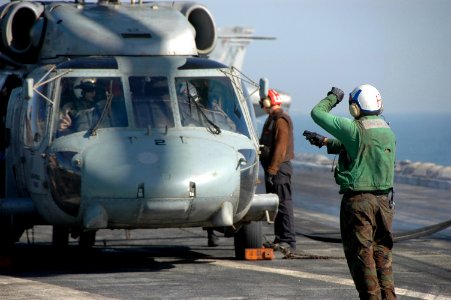 US Navy 070619-N-0890S-048 Aviation Ordnanceman Airman Richard Austin signals to the pilot of an SH-60F Seahawk helicopter prior to taking off on the flight deck of nuclear-powered aircraft carrier USS Nimitz (CVN 68)