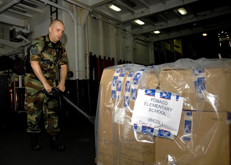 US Navy 070621-N-4954I-065 Air Force Staff Sgt. Christopher Stringer, attached to the 3rd Medical Support Squadron, moves a pallet of supplies aboard USS Peleliu (LHA 5)