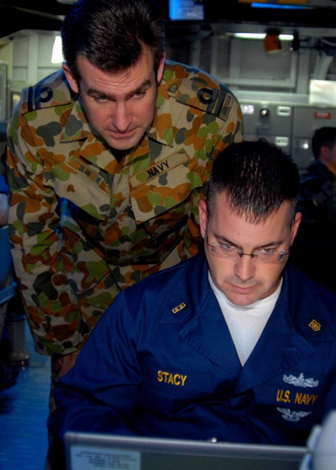 US Navy 070617-N-4124C-016 Lt. Richard N. Bean, meteorology and ocean officer for the Royal Australian Navy, looks over the shoulder of Chief Warrant Officer 2 Jon P. Stacy, force protection officer for Amphibious Squadron 11,