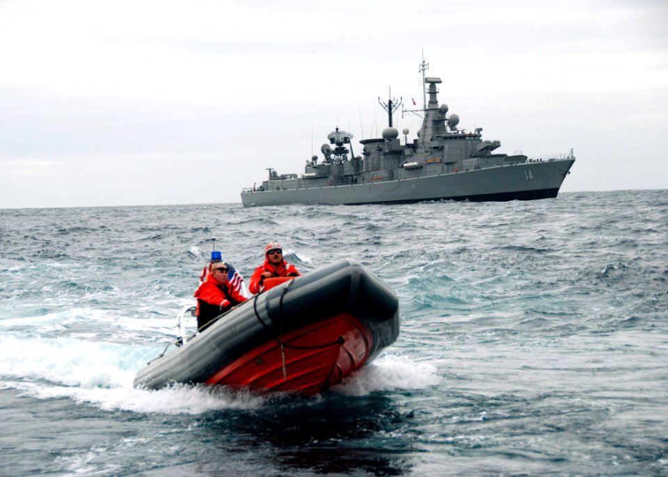 US Navy 070618-N-4021H-018 Chilean ship Almirante Latorre (FFG 14) sails in the distance while Coastguardsmen from U.S. Coast Guard Cutter Mohawk (WMEC 913) approach the stern gate of USS Pearl Harbor (LSD 52)