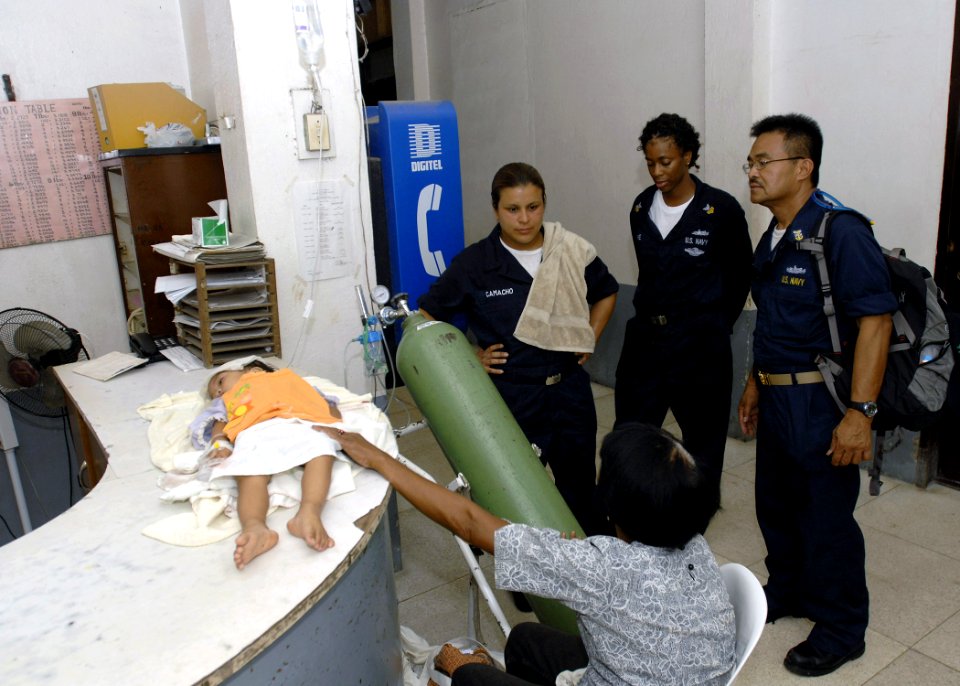 US Navy 070623-N-4954I-332 Sailors assigned to amphibious assault ship USS Peleliu (LHA 5) consult the mother of the sick child waiting for medical services at Ziga Memorial Hospital