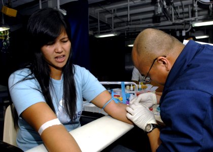 US Navy 070621-N-4954I-070 Air Force Tech Sgt. Richard Rubi draws blood from a Filipino patient aboard USS Peleliu (LHA 5)
