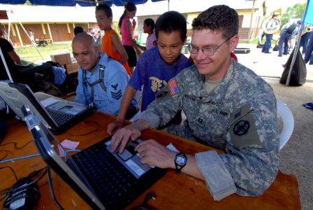 US Navy 070623-N-8704K-046 U.S. Army Capt. John Wishart, attached to the Military Sealift Command hospital ship USNS Comfort (T-AH 20), communicates with the ship as a young child watches photo