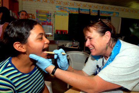 US Navy 070623-N-8704K-086 Peggy Goebel from of Project HOPE, a non-government organization embarked on the Military Sealift Command hospital ship USNS Comfort (T-AH 20), performs primary care a local child at the Monsignor Rom
