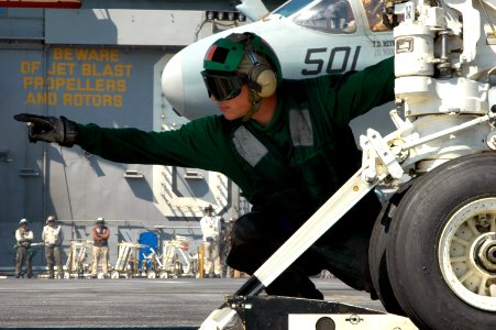 US Navy 070620-N-8119R-175 Aviation Boatswain's Mate (Equipment) 2nd Class Ricky Criswell signals that an F-A-18E Super Hornet, assigned to the Tophatters of Strike Fighter Attack Squadron (VFA) 14, is hooked up to the ca