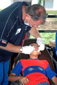 US Navy 070619-N-7783B-002 Cmdr. Greg Ganser, a Navy dentist assigned to Naval Operational Support Center, performs a routine dental exam on a student during a dental civil action project (DENCAP)