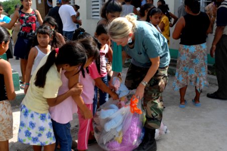 US Navy 070624-N-7088A-015 Air National Guardsman Senior Airman Holly Moore from the Military Sealift Command hospital ship USNS Comfort (T-AH 20) passes out toys to children in need of dental care