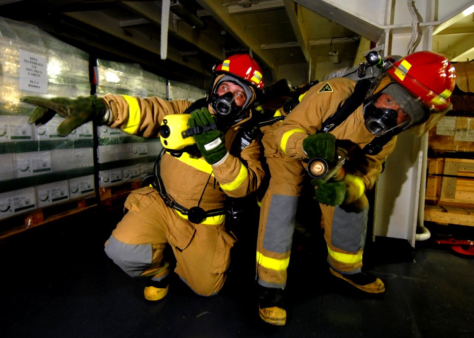 US Navy 070624-N-7981E-152 A hose team leader assigned to repair locker three uses a Naval Firefighter's Thermal Imager (NFTI) to direct a nozzleman to hotspots on a simulated class alpha fire in a storeroom aboard Nimitz-class