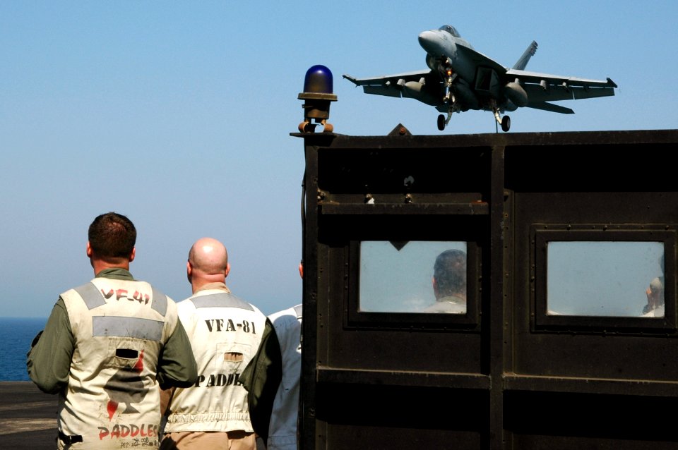 US Navy 070620-N-8119R-217 Landing signal officers watch an F-A-18E Super Hornet, assigned to the Tophatters of Strike Fighter Attack Squadron (VFA) 14, prepares to land on the flight deck
