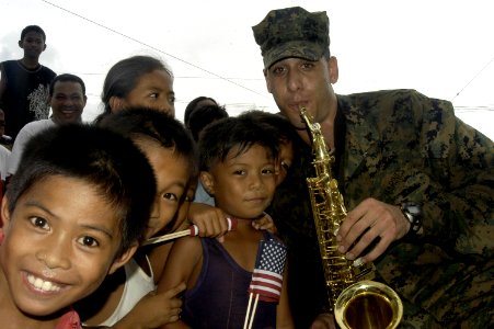 US Navy 070621-N-1752H-007 Cpl. Mark Pellon, of the U.S. Marine Forces Pacific Band, performs with local children during the Tabaco City Fair