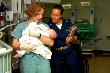 US Navy 070623-N-7088A-021 Lt. Kellie Kline holds young child as Capt. Wanda Richards looks on in a recovery room aboard the Military Sealift Command hospital ship USNS Comfort (T-AH 20) photo