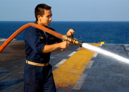 US Navy 070622-N-7955L-048 Midshipman 2nd Class Dale Davidson, from George Washington University, Washington, D.C., uses a hose to wash the flight deck of amphibious assault ship USS Kearsarge (LHD 3)