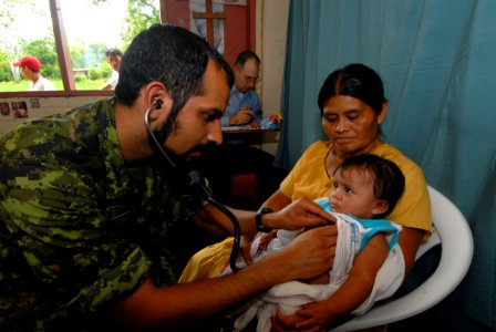 US Navy 070623-N-8704K-031 Canadian Army Lt. Syed Qadry, attached to the Military Sealift Command hospital ship USNS Comfort (T-AH 20), performs primary care for a child with his mother photo