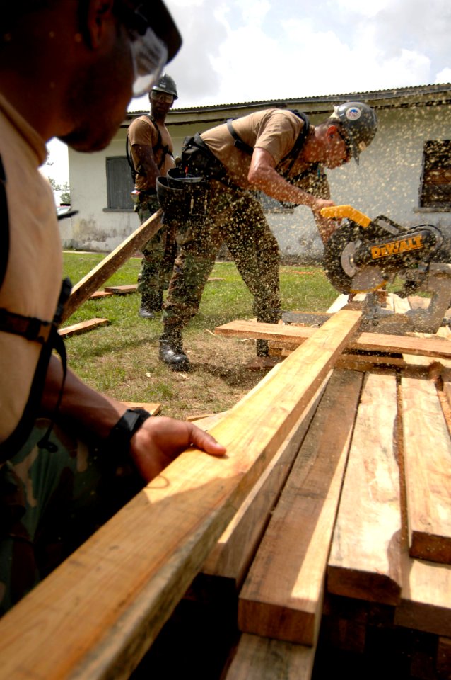 US Navy 070624-N-6278K-006 Steelworker 3rd Class Joel Washington, left, and Builder 2nd Class William Lathan, Construction Battalion Maintenance Unit (CBMU) 202, saw a board for a sidewalk at Belize Rural High School