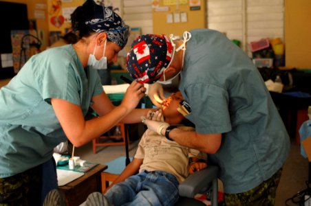 US Navy 070624-N-7088A-005 Capt. Tim Barter and Cpl. Marie-Claude Desharnais, members of the Canadian Forces, assigned to the Military Sealift Command hospital ship USNS Comfort (T-AH 20), perform dental work on a child photo