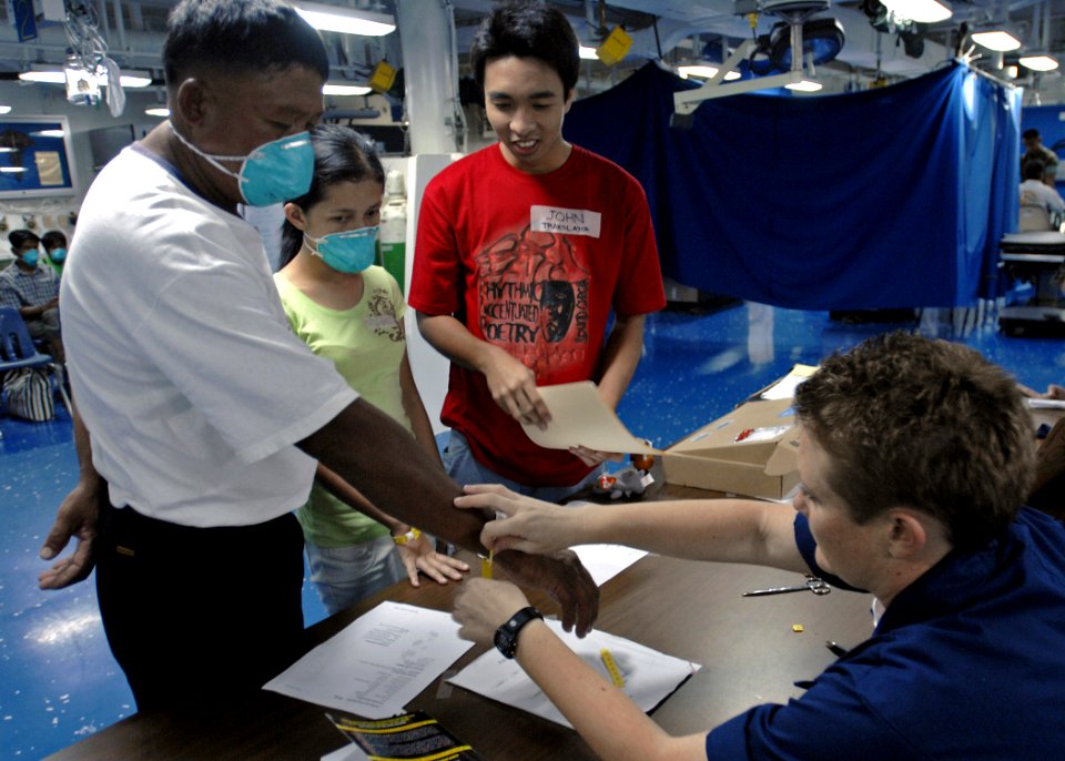 US Navy 070629-N-4954I-022 Hospital Corpsman 1st Class Cristin Quill puts a medical identification bracelet on a Filipino patient as he enters the medical ward of USS Peleliu (LHA 5)